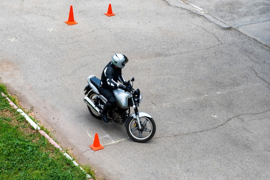 Person practising their motorcycling skills with orange cones around them